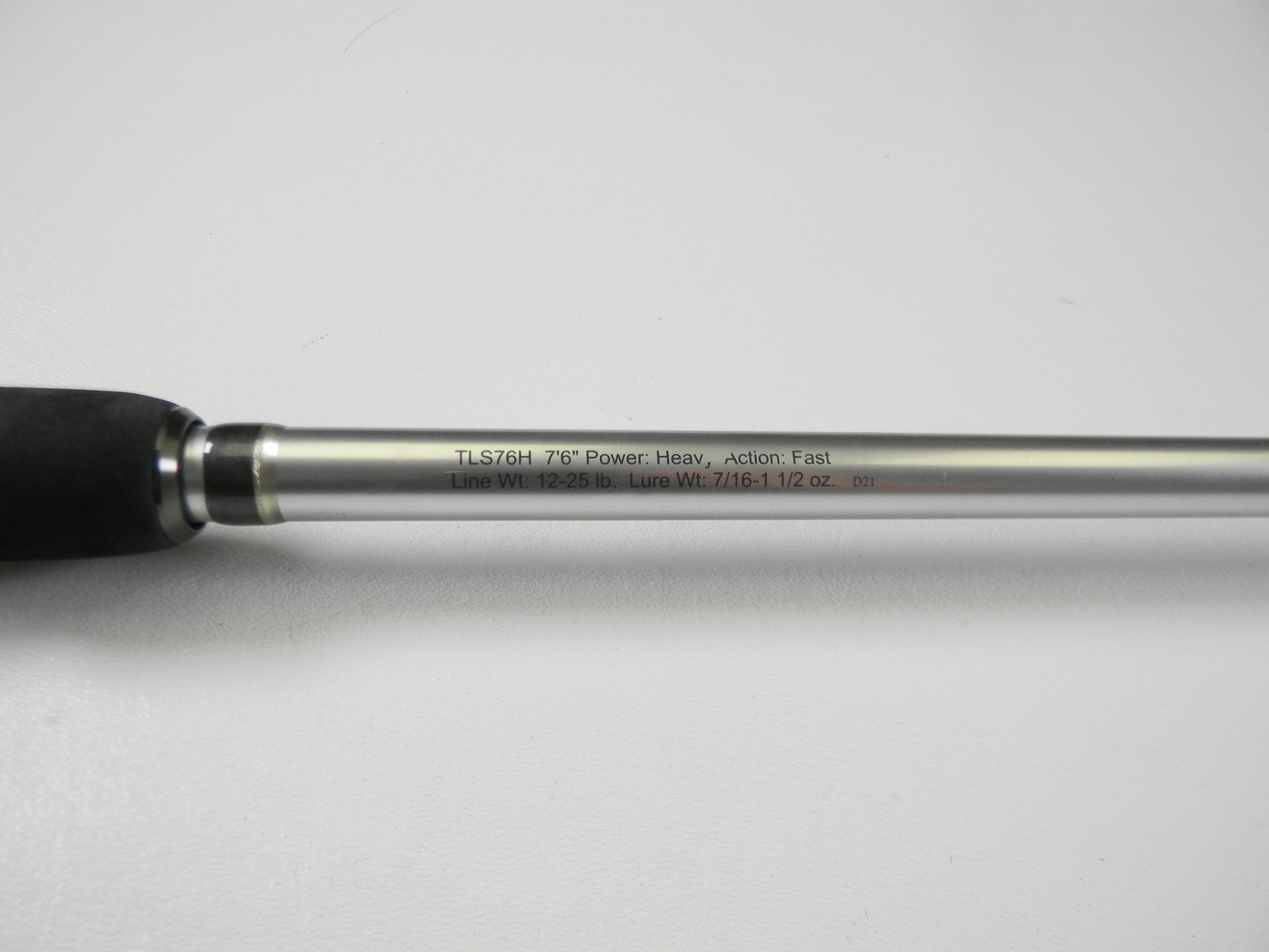 Close-up of the Lew's Signature Series TLS76H Pitching 7'6" Heavy Casting Rod, engraved with details and featuring a black foam grip and silver shaft. This used rod is in excellent condition and eligible for our Rod and Reel Trade-In Program for store credit.