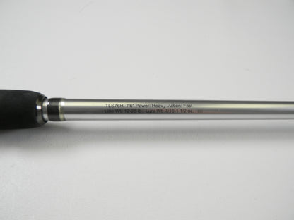 Close-up of the Lew's Signature Series TLS76H Pitching 7'6" Heavy Casting Rod, engraved with details and featuring a black foam grip and silver shaft. This used rod is in excellent condition and eligible for our Rod and Reel Trade-In Program for store credit.