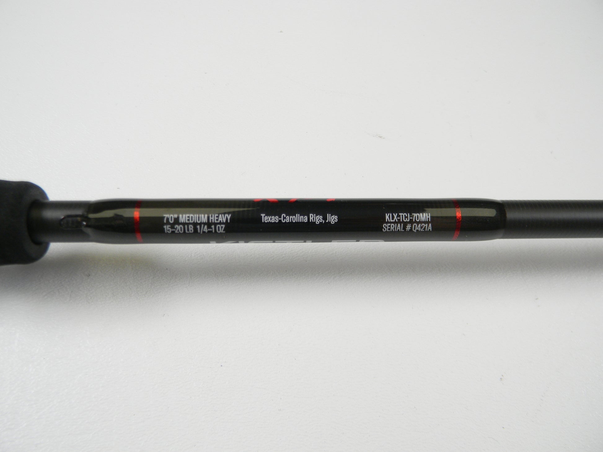 Close-up of a Lew's Kistler KLX KLX-TCJ-70MH casting rod in excellent condition shows "7'0” Medium Heavy," supports "15-20 lb" and "1/4-1 oz," good for Texas-Carolina Rigs and Jigs. Visible model number is “KLX-TC3-70MH” with serial "#04214." Ideal for trading up through our Rod and Reel Trade-In Program.