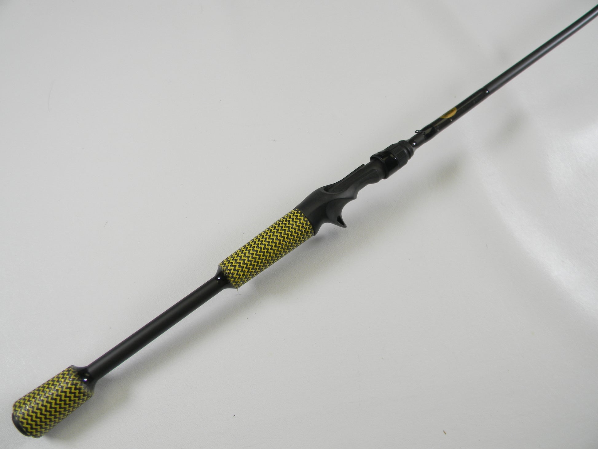 The Kistler Cashion P84469b 6'9" Medium Heavy Casting Rod, with black and yellow textured grip handles and a sleek black finish, is shown diagonally on a white background. Ideal for our Rod and Reel Trade-In Program, it offers exciting upgrades to your used gear.