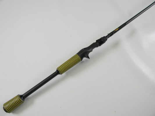 The Kistler Cashion P84469b 6'9" Medium Heavy Casting Rod, with black and yellow textured grip handles and a sleek black finish, is shown diagonally on a white background. Ideal for our Rod and Reel Trade-In Program, it offers exciting upgrades to your used gear.