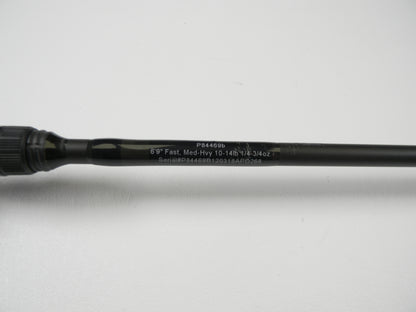 The Cashion P84469b 6'9" Medium Heavy used casting rod, in good condition, features details like "Fast, 10-14lb, 1/2-3/4oz" and the serial number "P84469B120318APO268." It's ideal for a rod and reel trade-in to earn store credit. The sleek black shaft is displayed on a white surface.