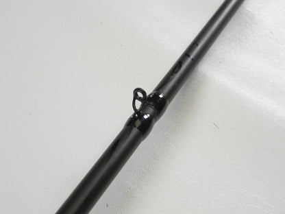 A close-up of a Cashion F90474b 7'4" Medium Heavy used casting rod in very good condition, lying on a white surface, highlights a black line guide loop. This fishing rod may qualify for our Rod and Reel Trade-In Program.