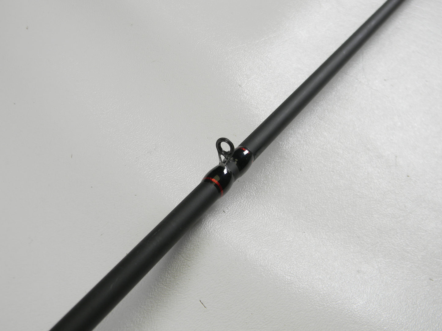A close-up of a Falcon EVO VFC-7-173 7'3" Heavy Casting Rod in excellent condition is shown against a white background. This black rod, with red-accented eyelets, qualifies for our Rod and Reel Trade-In Program.
