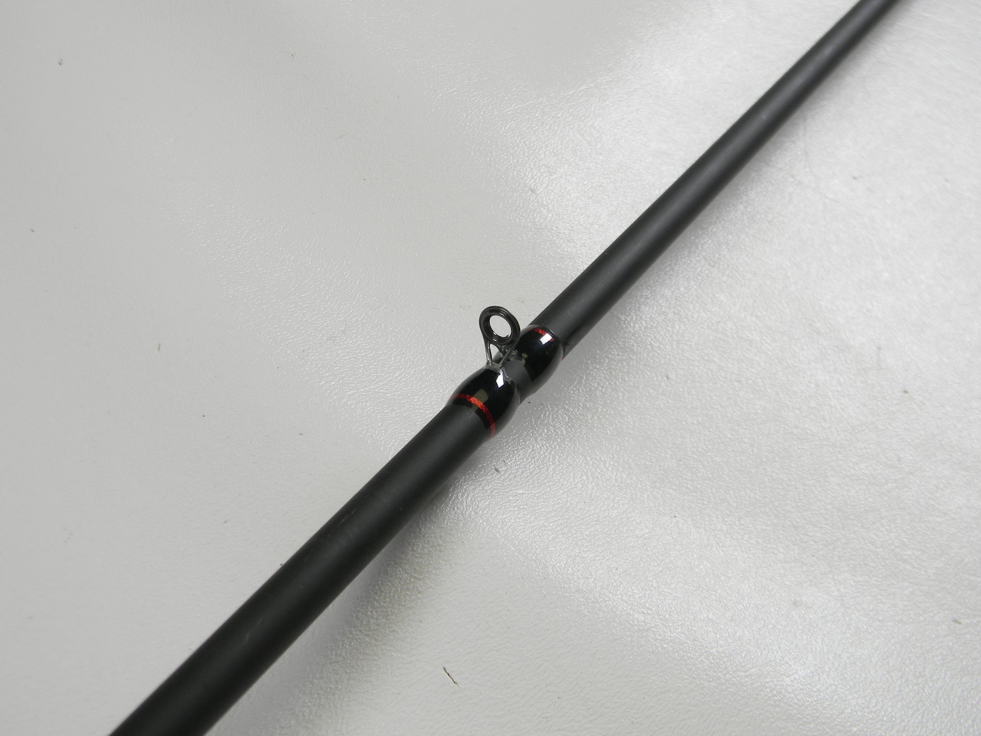 A close-up of a Falcon EVO VFC-7-173 7'3" Heavy Casting Rod in excellent condition is shown against a white background. This black rod, with red-accented eyelets, qualifies for our Rod and Reel Trade-In Program.