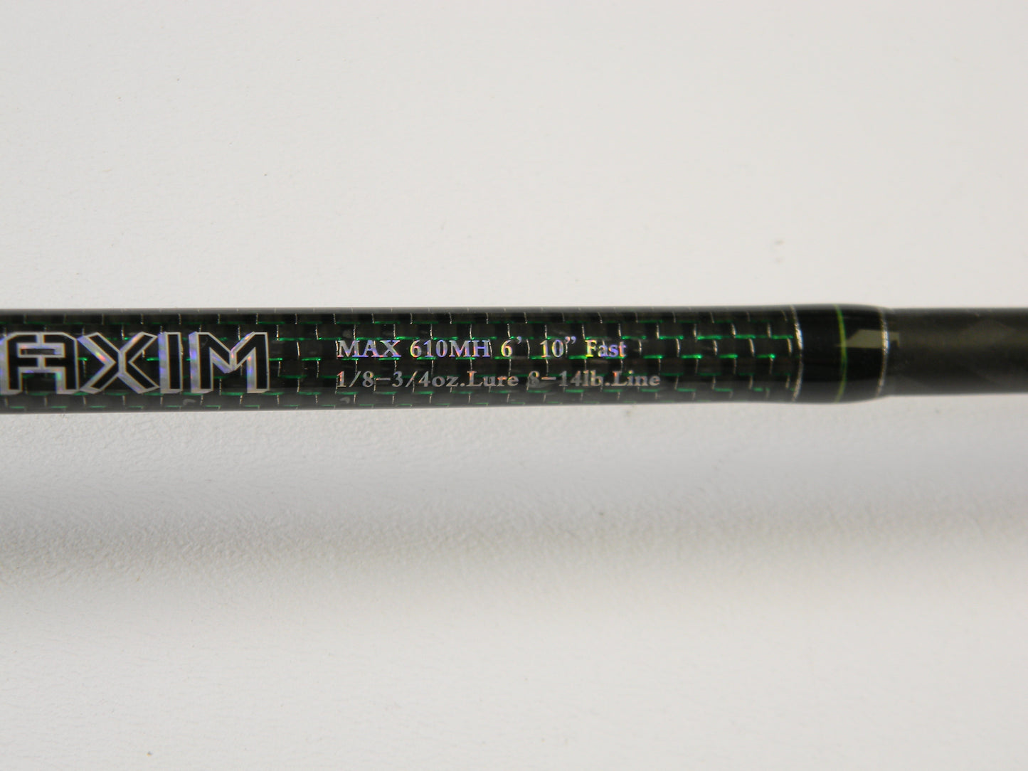 Close-up of a Phenix Maxim PHX-MAX-C610MH 6'10" Medium Heavy casting rod with "MAX 610MH 6'10" Fast 1/8 - 3/4oz. Lure 6 - 14lb. Line" in green and white, featuring "AXIM" prominently. Ideal for our Rod and Reel Trade-In Program—upgrade your used gear for store credit today!.