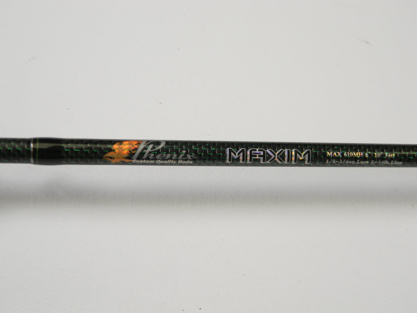 Close-up of a Phenix Maxim PHX-MAX-C610MH 6'10" Medium Heavy Fishing Rod, highlighting carbon fiber texture and detailed specs. Consider trading your used gear through our Rod and Reel Trade-In Program for store credit. Background is plain white.