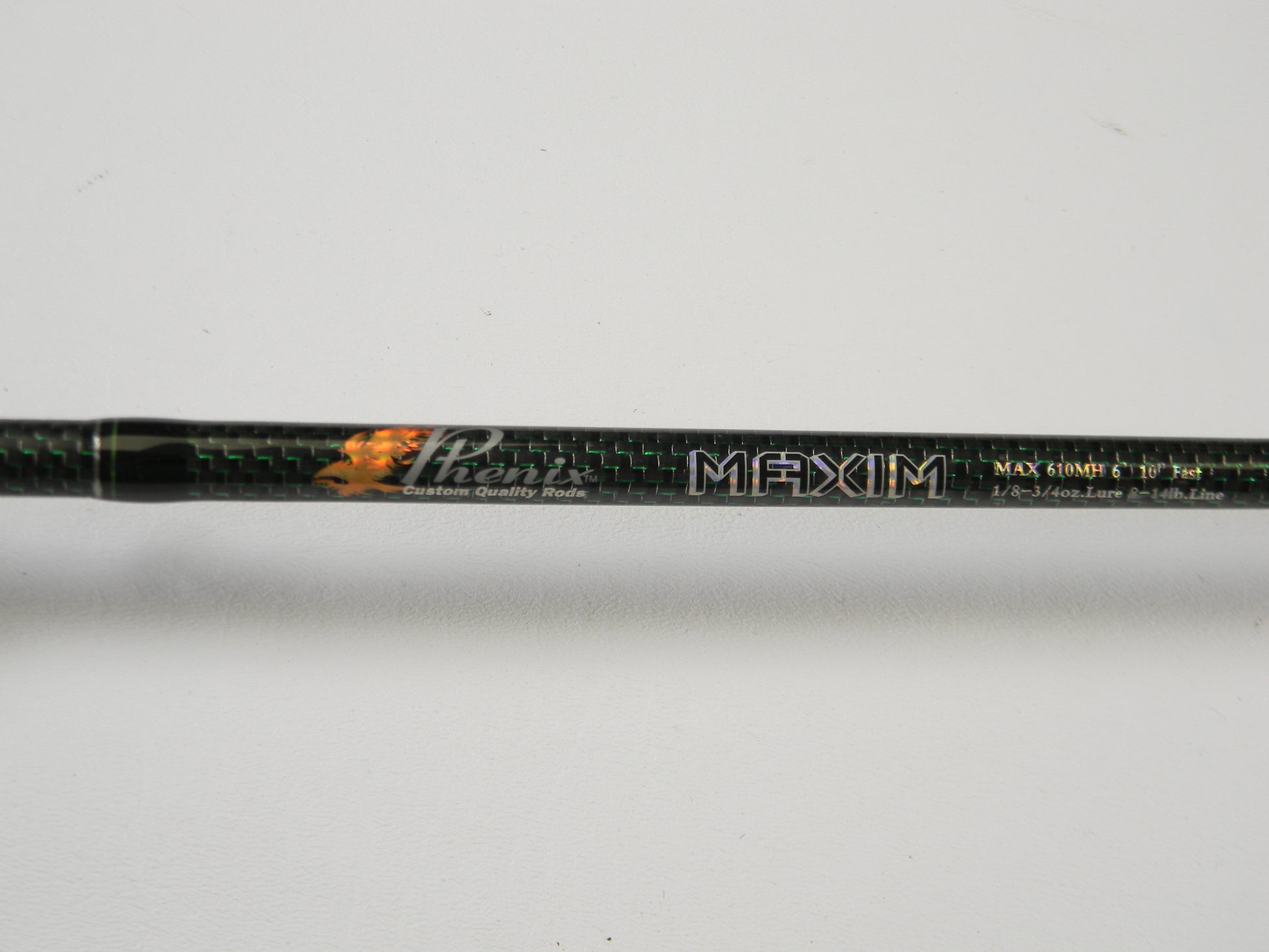 Close-up of a Phenix Maxim PHX-MAX-C610MH 6'10" Medium Heavy Fishing Rod, highlighting carbon fiber texture and detailed specs. Consider trading your used gear through our Rod and Reel Trade-In Program for store credit. Background is plain white.