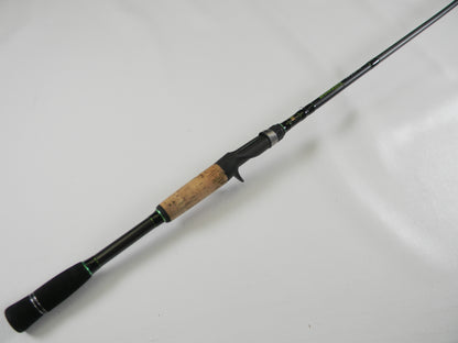 The Dobyns Fury FR734C, a sleek 7'3" black and green fishing rod with a cork grip handle, lies diagonally on a white surface. This lightweight used casting rod is in excellent condition and part of our Rod and Reel Trade-In Program, perfect for optimal casting.