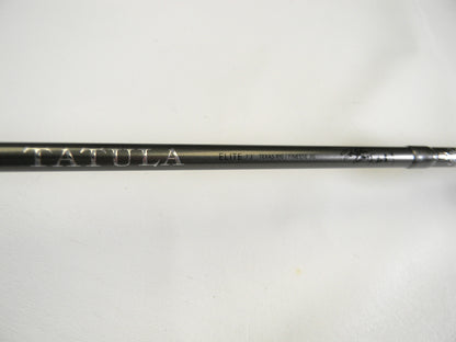 Close-up of a black Daiwa Tatula Elite TTEL731HFB Texas Rig/Finesse Jig 7'3" Heavy rod with "TATULA" and "ELITE" printed in white. The smooth, light backdrop highlights its craftsmanship, making it perfect for our Rod and Reel Trade-In Program for those upgrading used gear with store credit.