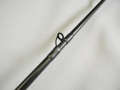 Close-up of a Daiwa Tatula Elite TTEL751MHFB, highlighting its metal guide ring on a dark pole against a light background. Perfect for our Rod and Reel Trade-In Program participants seeking quality gear, this 7'5" medium-heavy used rod is in mint condition.