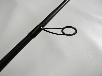 Close-up of the Ark Invoker Pro IVP71MXS 7'1" Medium - Used Spinning Rod in excellent condition, showcasing its textured finish and shiny metal guiding ring on a smooth white surface, embodying Ark Fishing's commitment to quality through our Rod and Reel Trade-In Program.