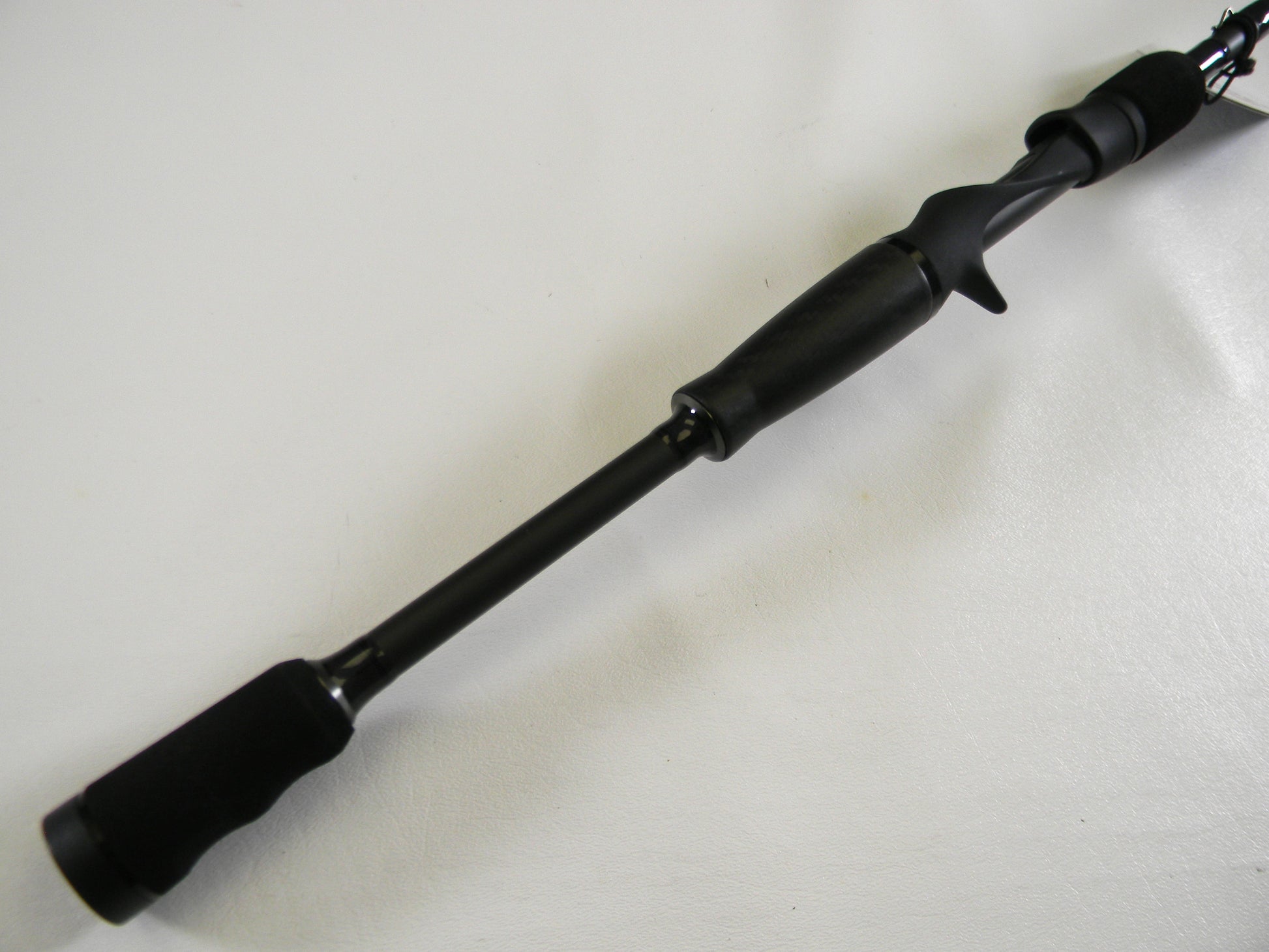 Close-up of the Abu Garcia Veritas Tournament VXTC72-5 black handle against a white background. This used casting rod features a comfortable trigger grip design. Perfect for upgrading in our Rod and Reel Trade-In program with generous store credit offers.