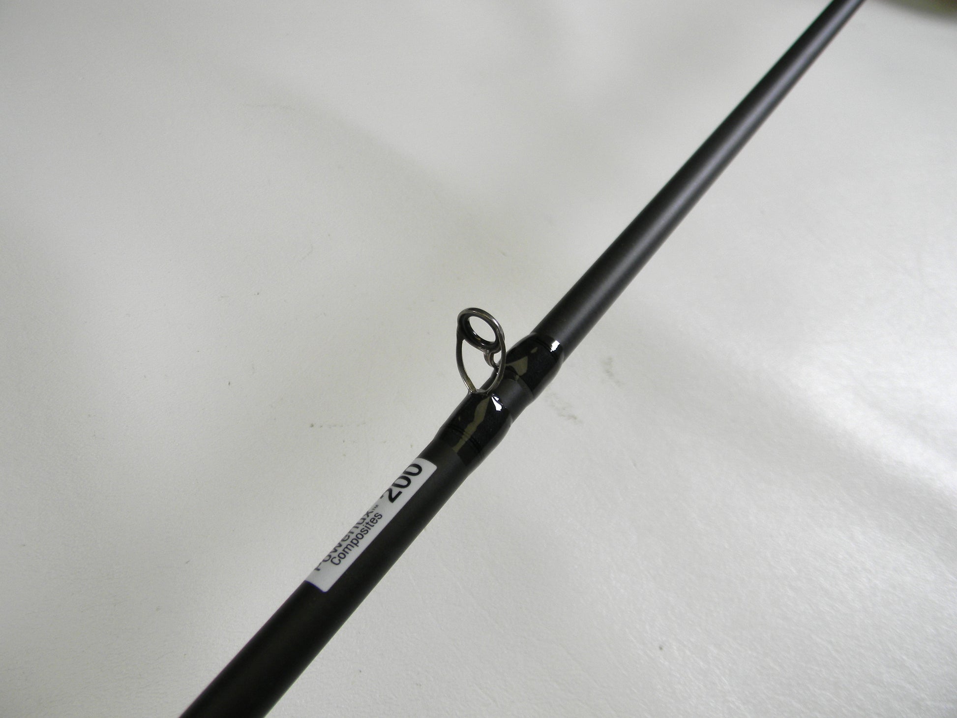 A close-up of the Abu Garcia Veritas Tournament VXTC72-5 7'2" Medium casting rod, featuring a line guide labeled "202" to signify its quality. This used gear, set against a light plain backdrop, qualifies for our Rod and Reel Trade-In program.