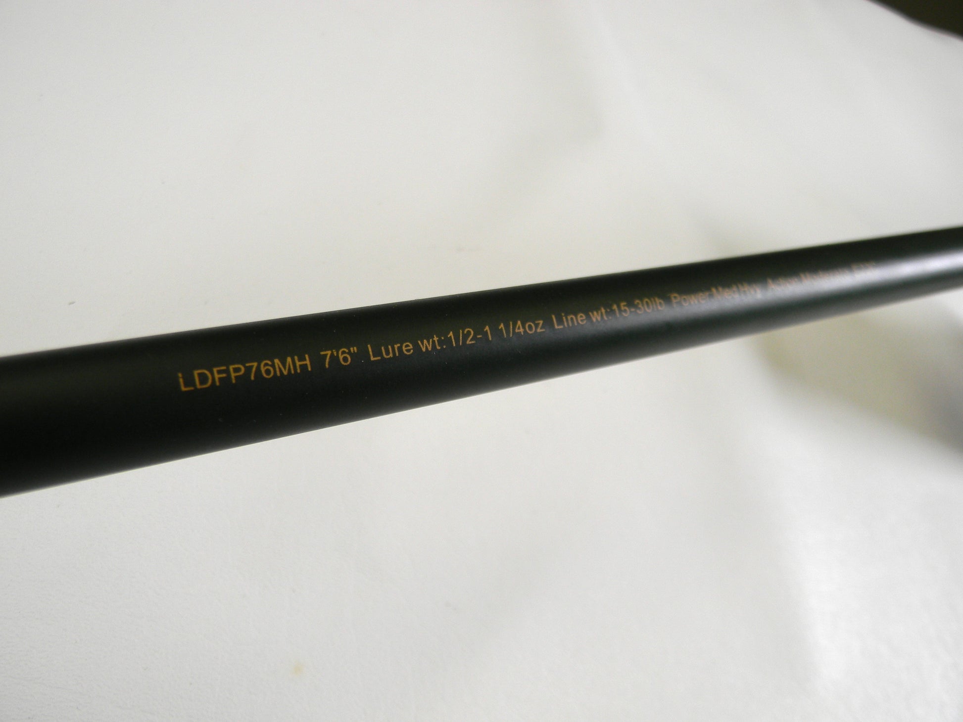 A close-up of the Lew's David Fitts Perfect Crankbait LDFP76MH 7'6" Medium Heavy rod shows text: "Lure wt: 1/2-1 1/4oz Line wt: 15-30lb." Against a plain white background, it could be perfect for your next Rod and Reel Trade-In.