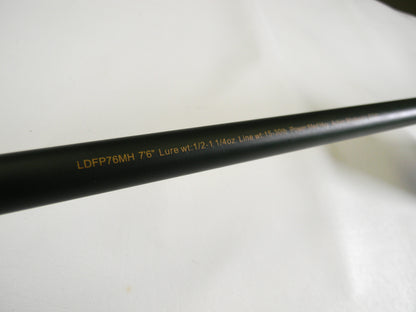 A close-up of the Lew's David Fitts Perfect Crankbait LDFP76MH 7'6" Medium Heavy rod shows text: "Lure wt: 1/2-1 1/4oz Line wt: 15-30lb." Against a plain white background, it could be perfect for your next Rod and Reel Trade-In.