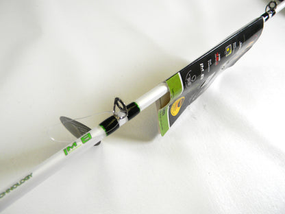 Close-up of a used Lew's Mach 1 MH1SHA610MH 6'10" Medium Heavy casting rod, mint condition, with green and black accents. It is angled diagonally on a white surface with tags showing partial logos and text as part of our Rod and Reel Trade-In Program.