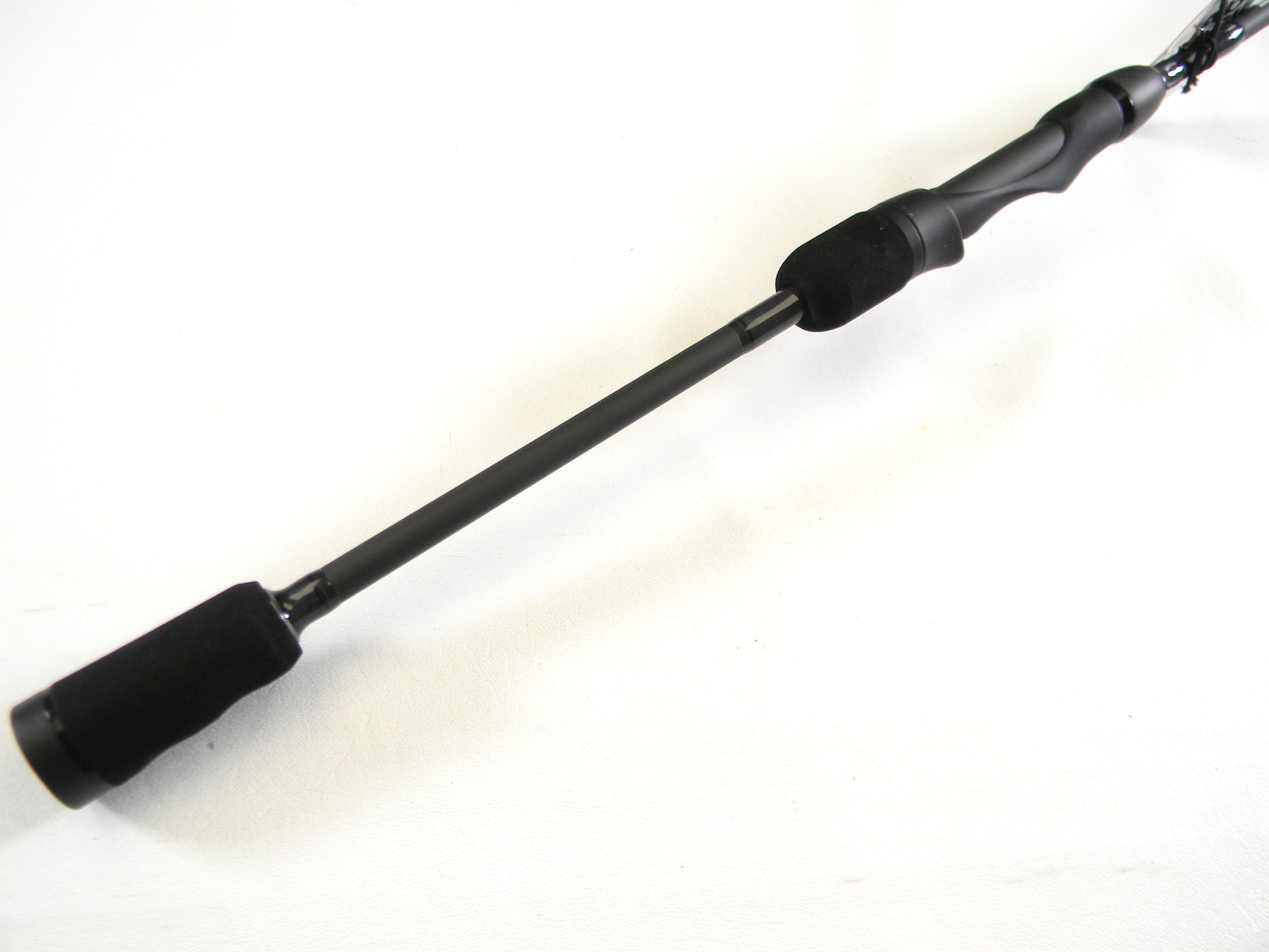 Close-up of the Abu Garcia Veritas Tournament VXTS610-4 spinning rod in mint condition on a white background. Ideal for trading in used gear, this sleek black rod with a smooth handle and cylindrical grip can earn you credit through our Rod and Reel Trade-In program.