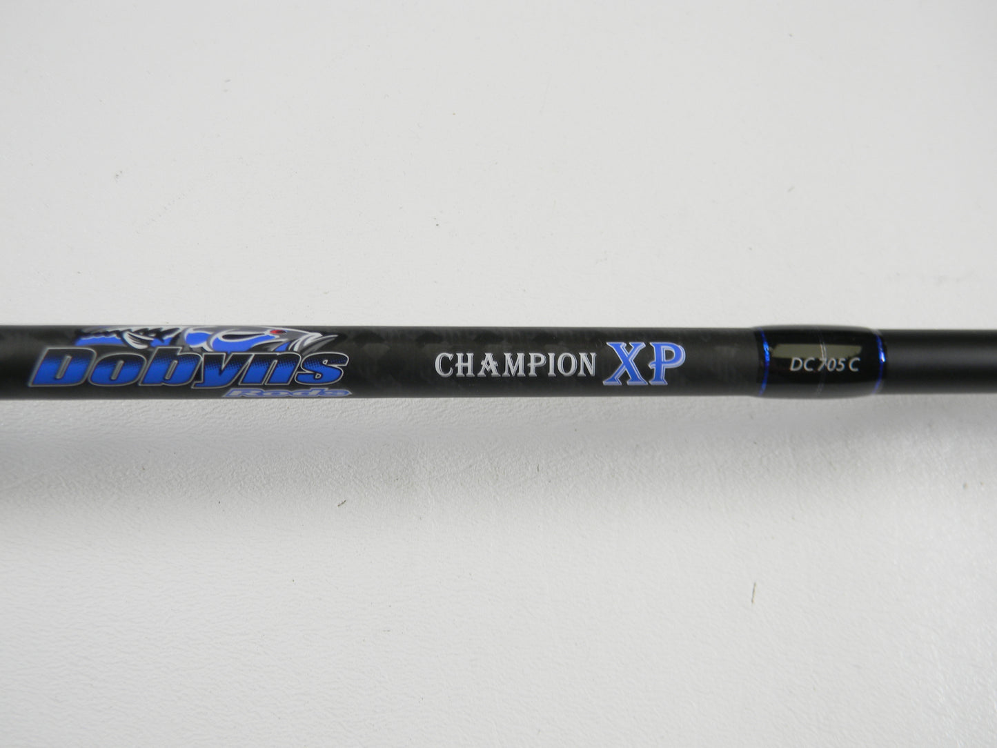 A close-up of a Dobyns Champion XP DC705C 7'0" Mag Heavy Used Casting Rod in excellent condition, featuring blue and white lettering on a black rod, photographed against a white background—ideal for anglers trading up with our Rod and Reel Trade-In Program.