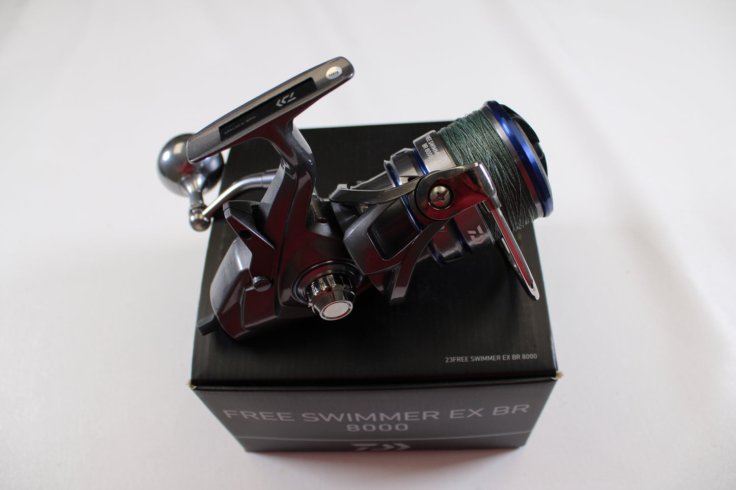 A Daiwa Free Swimmer EX BR 8000 used spinning reel in excellent condition with green line sits on a black box against a white background—ideal for anglers upgrading via rod and reel trade-in programs.