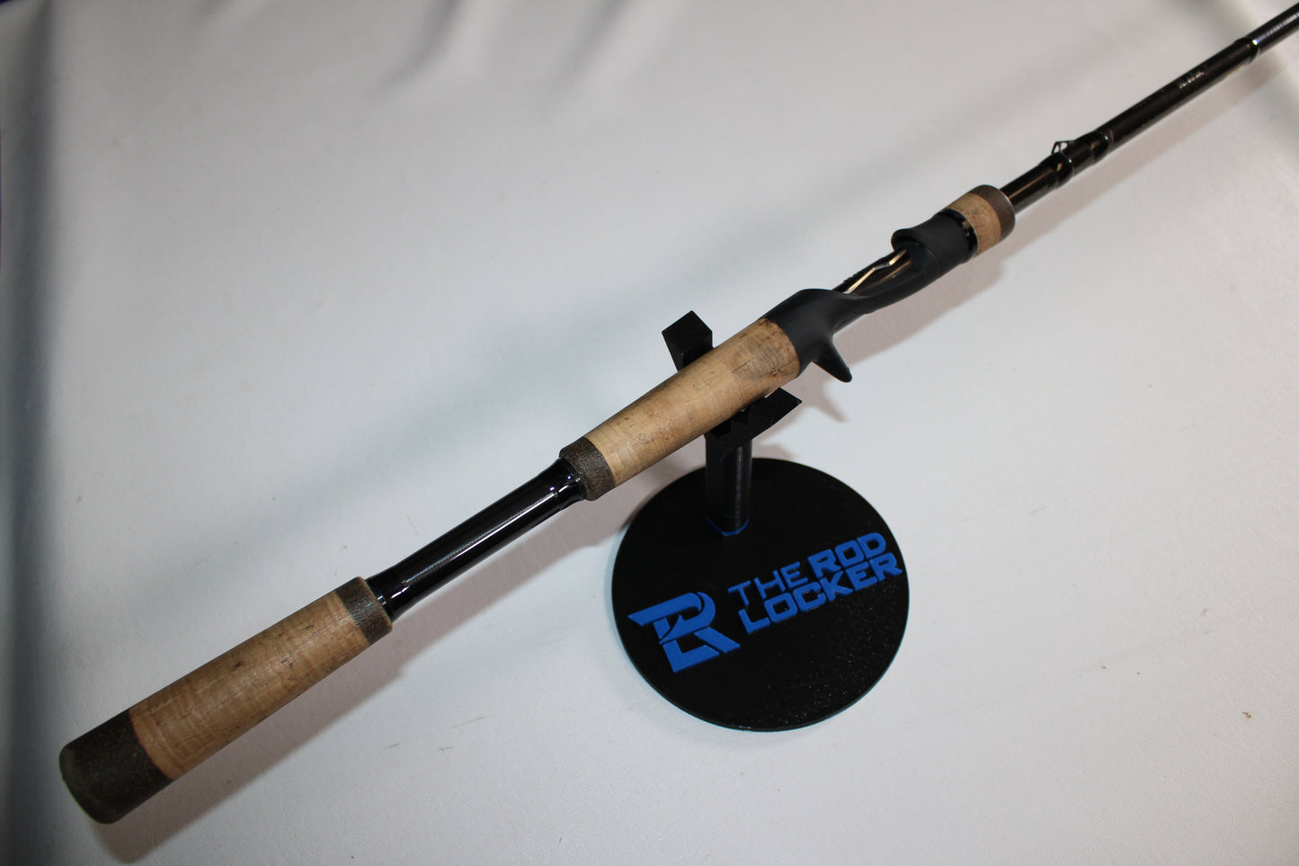 A 13 Fishing Envy Black EB3C79C Used Casting Rod (Good Condition) with a cork handle is displayed on a black stand labeled "The Rod Locker" against a plain white background.