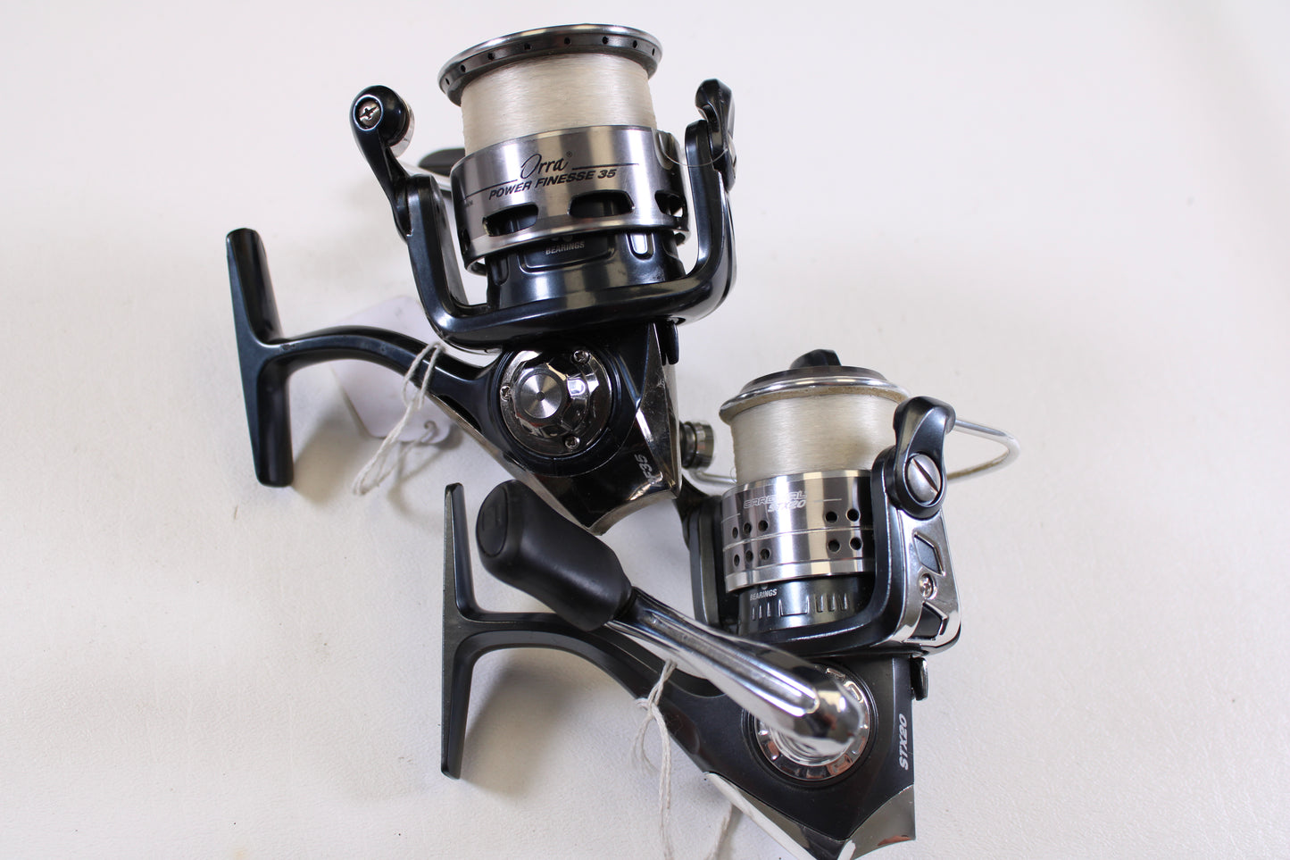 Two used Abu Garcia spinning reels (Orra Power Finesse 35 & Cardinal STX20) in good condition, silver and black with line—great for your next rod and reel trade-in or to upgrade your fishing gear collection.