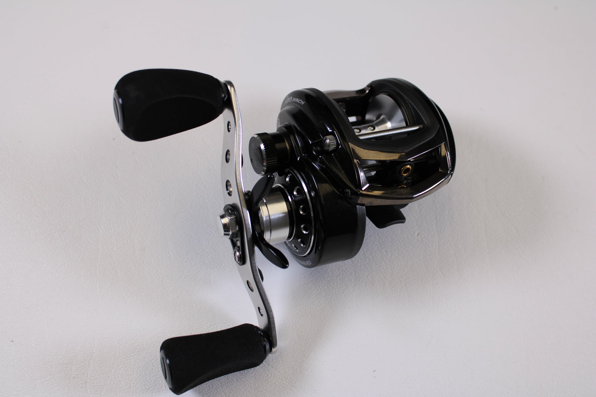A close-up of the Abu Garcia Revo Winch Gen 2 5.4:1 RH Used Casting Reel in excellent condition, featuring padded handles against a white background—ideal for those exploring our Rod and Reel Trade-In Program or quality pre-owned gear.