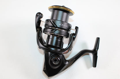 A close-up of the Shimano Sustain FJ SA4000XGFJ 6.2:1 Used Spinning Reel in Mint Condition, angled to display its handle and spool, perfect for trade-in or store credit. The black Shimano reel is set against a plain white background.