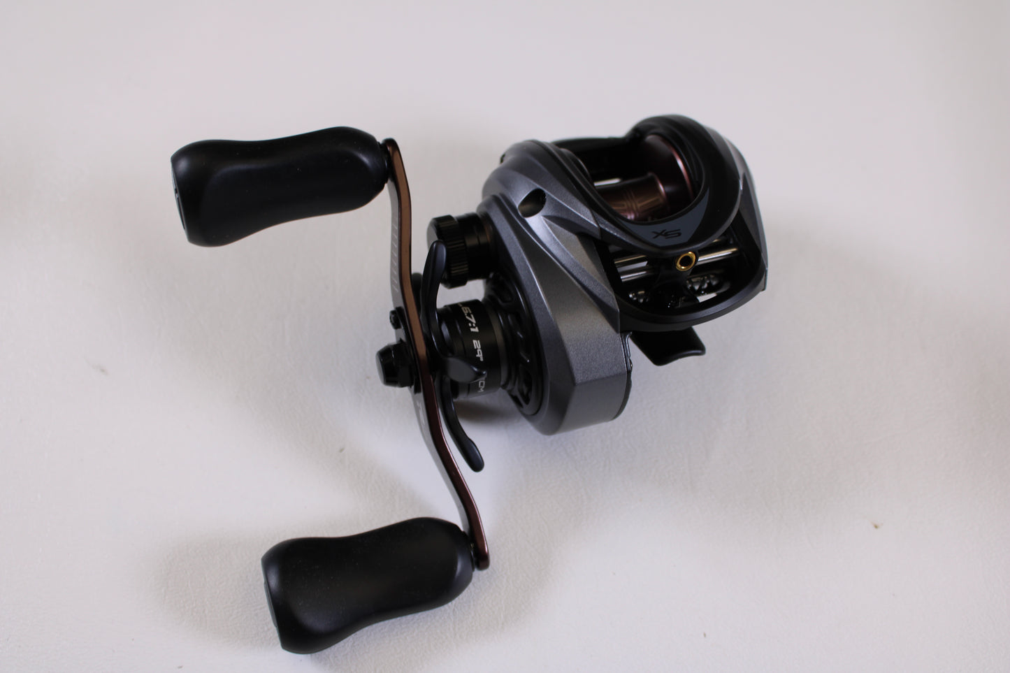 A close-up of an Abu Garcia Revo SX REVO5 SX LP 6.7:1 RH Used Casting Reel in excellent condition with two ergonomic handles, shown on a white surface—ideal for our Rod and Reel Trade-In Program if upgrading your gear.