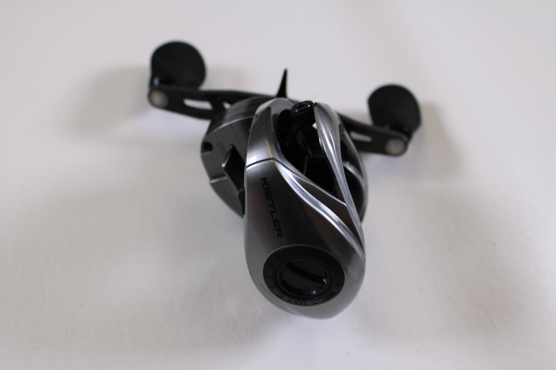 A close-up of a black Kistler Chromium 7.3:1 RH Used Casting Reel in excellent condition with dual handles on a white surface—ideal for our Rod and Reel Trade-In Program or quality used gear options.