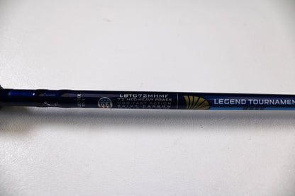 A close-up of a St. Croix Legend Tournament Bass LBTC72MHMF Finesse Carbon Cranker 7'2" Medium Heavy Used Casting Rod in excellent condition, with a USA flag emblem and Rod & Reel Trade-In Program details on metallic blue.