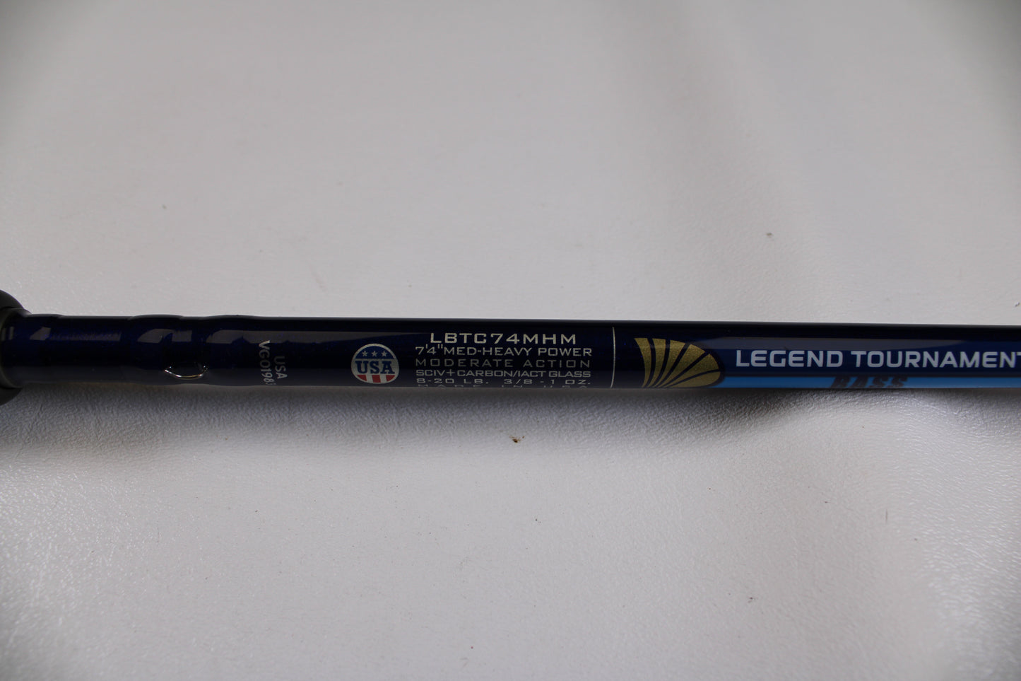 Close-up of a blue St. Croix Legend Tournament Bass LBTC74MHM Power Glass Cranker 7'4" Med-Heavy Casting Rod, Used in Excellent Condition, with "MODERATE ACTION" and USA logo visible on a white background.