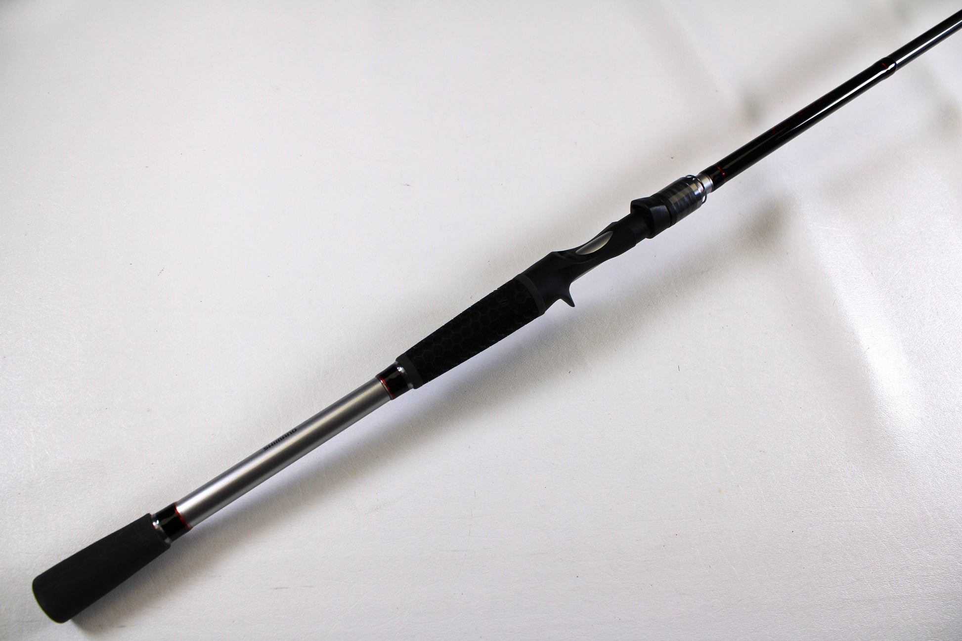The Shimano Intenza NTZC78XH 7'8" XH Used Casting Rod, in excellent condition, is displayed diagonally on a plain white background. The rod features black and silver accents with a black grip handle.