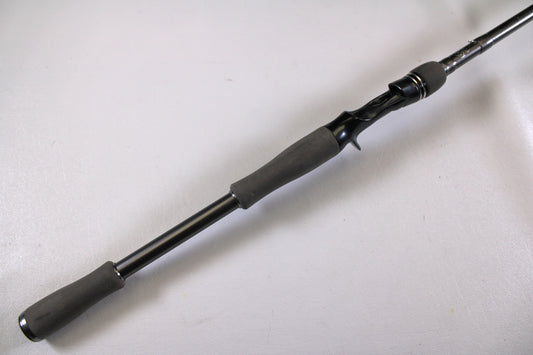 A close-up of the Daiwa Tatula Elite TTEL741MHRB-G 7'4" casting rod’s black and gray handle and reel seat, highlighting its very good used condition, is shown against a plain white background.