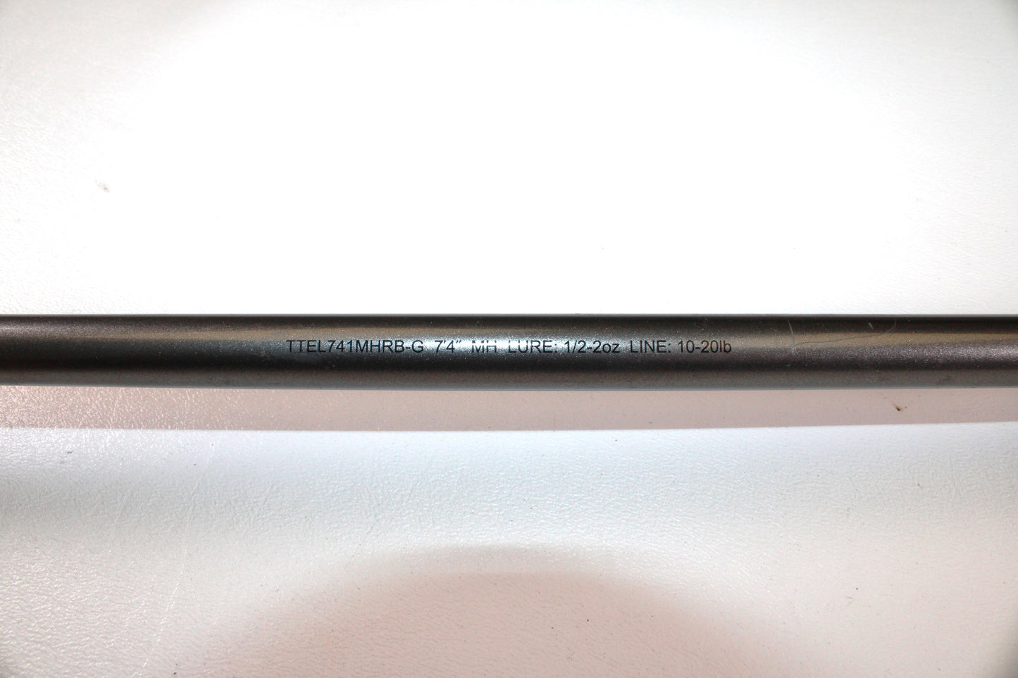 Close-up of a Daiwa Tatula Elite TTEL741MHRB-G 7'4" Medium Heavy Used Casting Rod in very good condition, resting on a white surface. Eligible for our Rod and Reel Trade-In Program for store credit.
