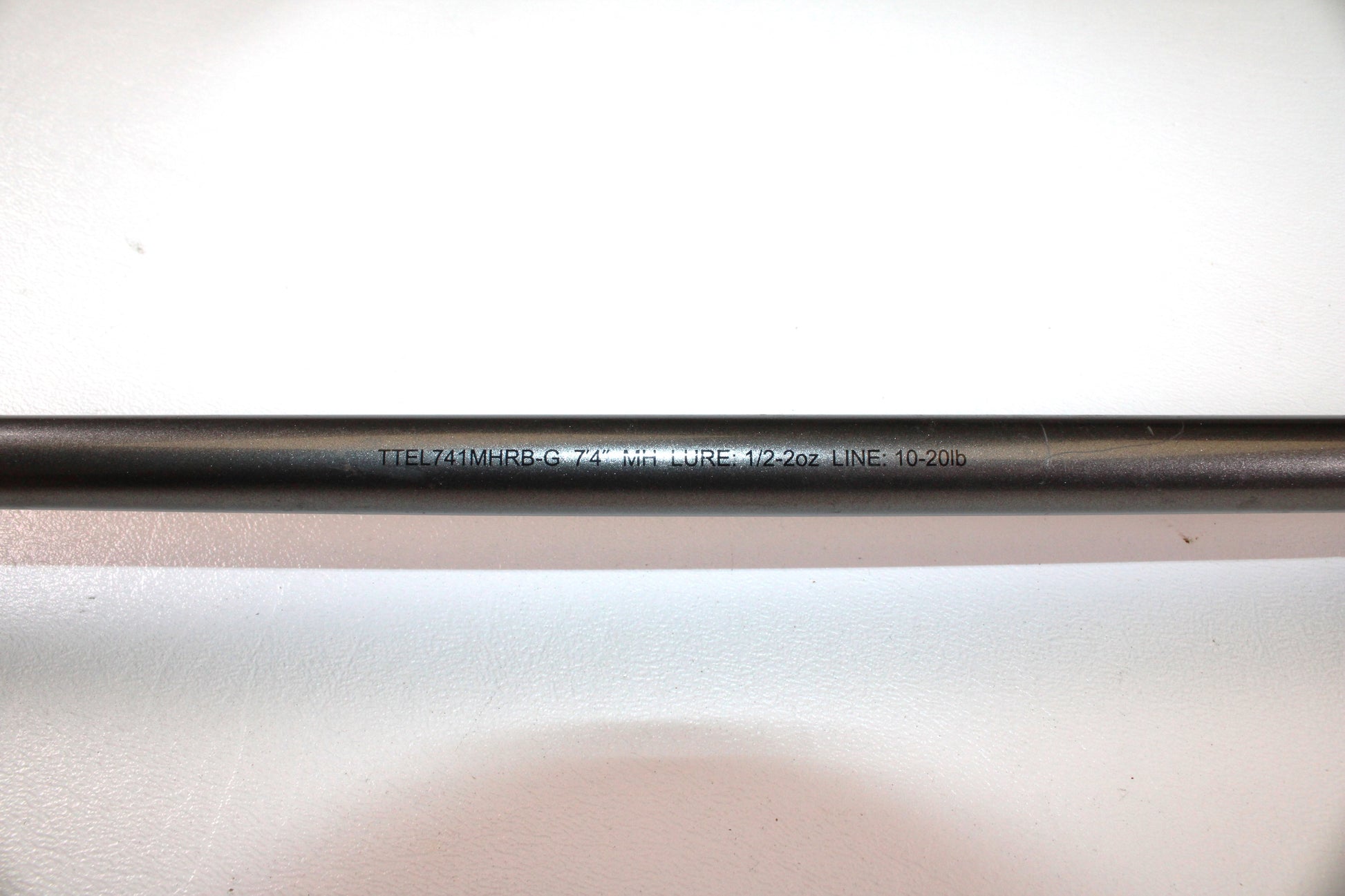 Close-up of a Daiwa Tatula Elite TTEL741MHRB-G 7'4" Medium Heavy Used Casting Rod in very good condition, resting on a white surface. Eligible for our Rod and Reel Trade-In Program for store credit.