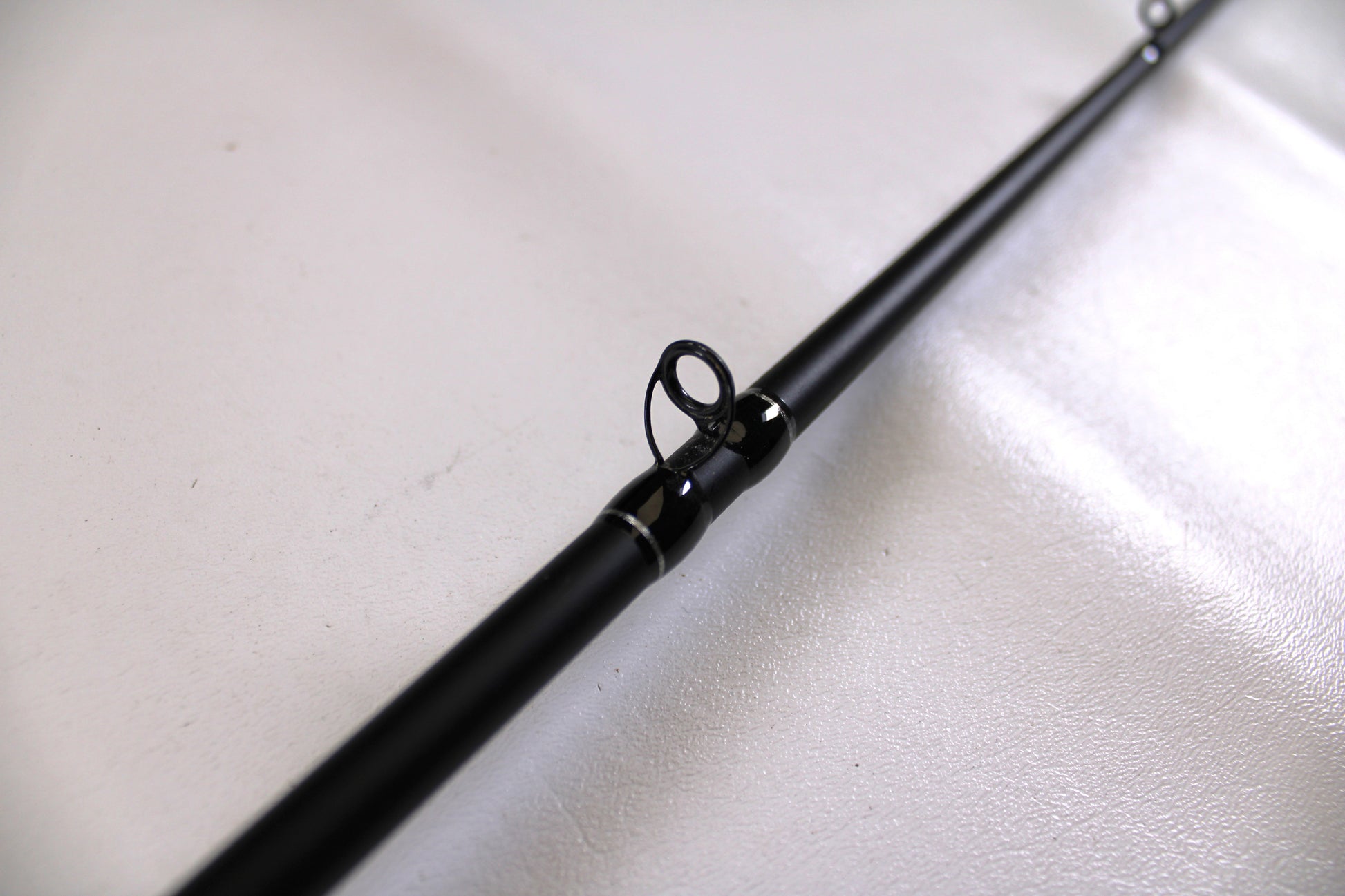 A detailed close-up of the Enigma Ippon EIPN7MB-MH 7'0" Medium Heavy Used Casting Rod in Excellent Condition, highlighting a guide ring against a white background—ideal for assessing used gear for our Rod and Reel Trade-In Program.