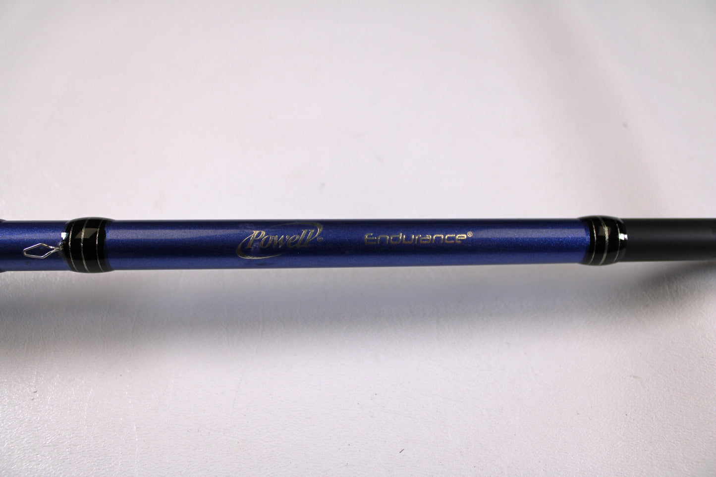 A close-up of a Powell Endurance 755 CB Mod-Fast 7'5" Medium Heavy Used Casting Rod in very good condition, featuring gold "Powell Endurance" lettering on blue—ideal for those exploring the Rod and Reel Trade-In Program or used gear options.