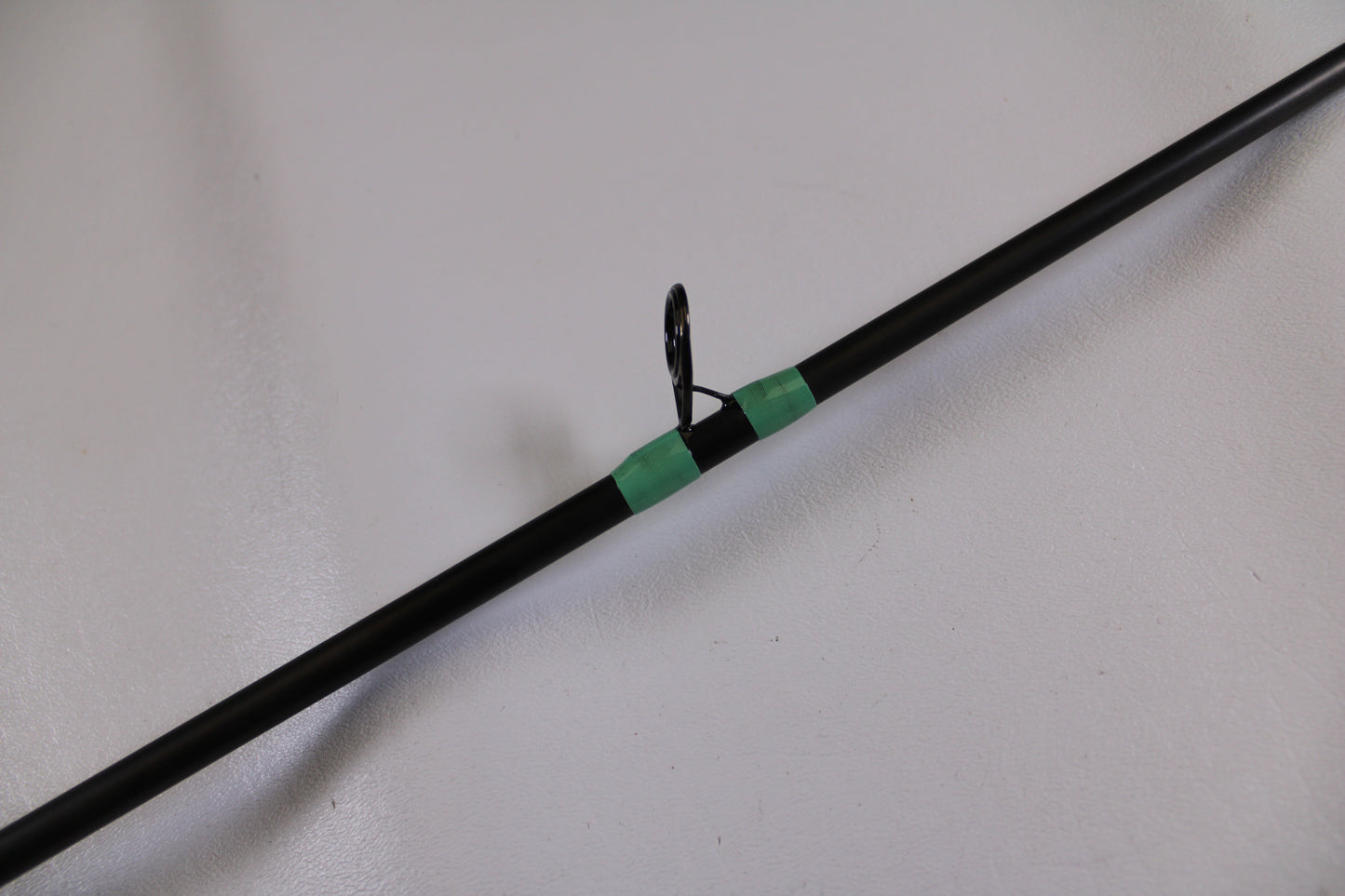A close-up of the G. Loomis GCX Inshore 842C MF Used Casting Rod in excellent condition, featuring a guide ring wrapped with green thread—ideal for those interested in used G. Loomis gear or our Rod and Reel Trade-In Program.
