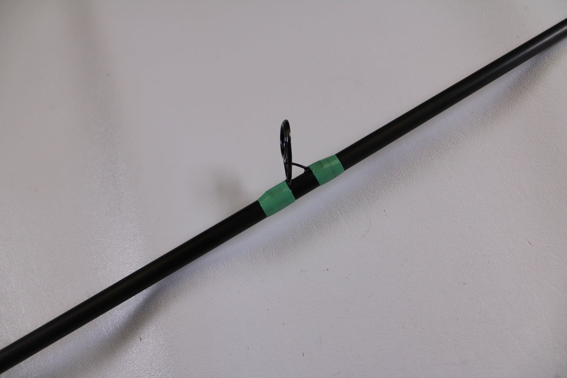 A close-up of the G. Loomis GCX Inshore 842C MF Used Casting Rod in excellent condition, featuring a guide ring wrapped with green thread—ideal for those interested in used G. Loomis gear or our Rod and Reel Trade-In Program.