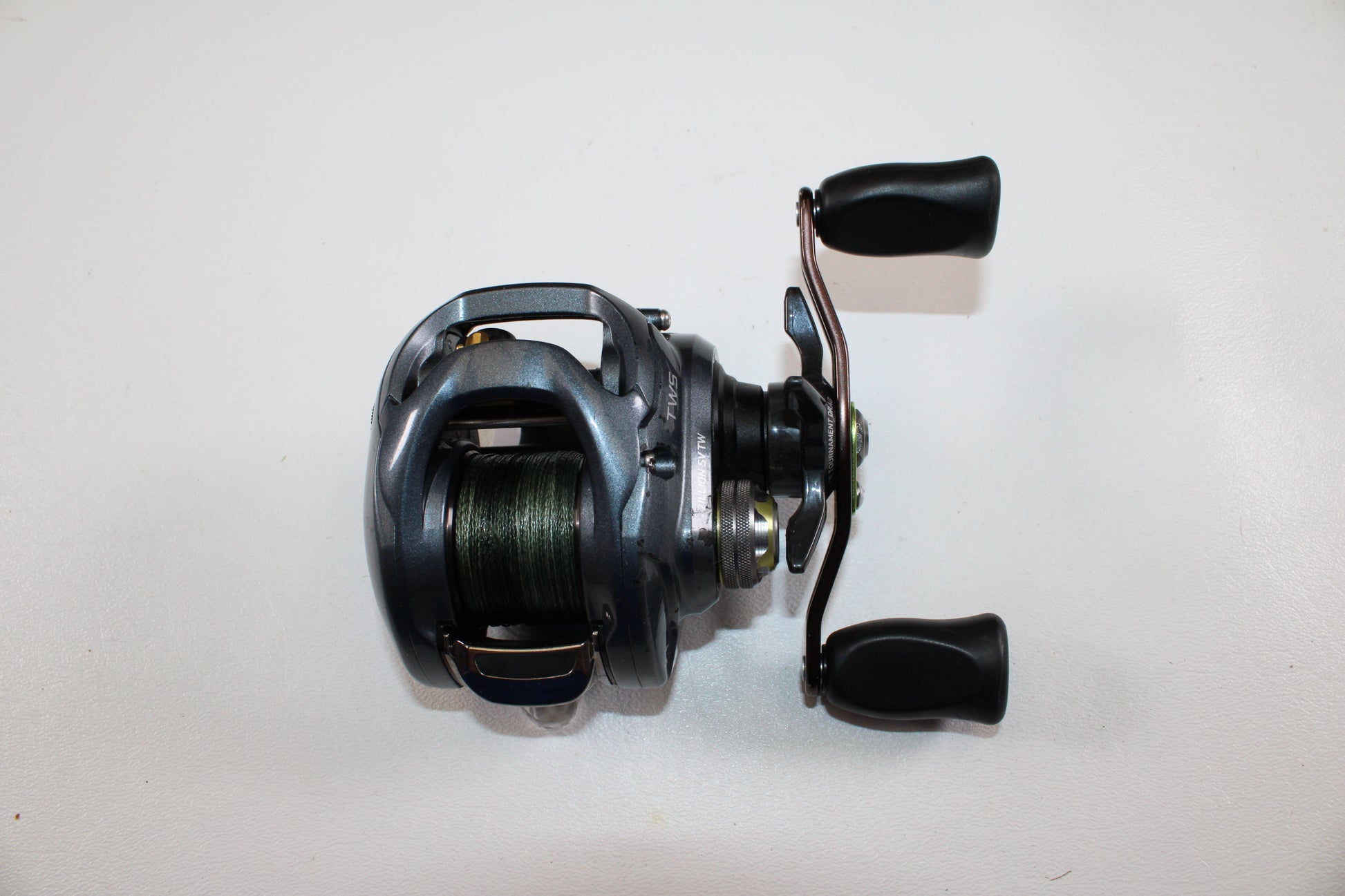 Upgrade with our Rod and Reel Trade-In Program or earn store credit on used gear—like this Daiwa Zillion SV TW JDM 9.1:1 Gear Ratio casting reel (used, good condition) by Daiwa, shown with black handles and green line on a white background.