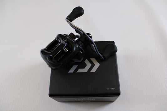A Daiwa Tatula 150 TAT150HSL Used Casting Reel from our used gear collection sits atop a black box with white logo and text, set against a plain white background. Explore our Rod and Reel Trade-In program or store credit options.