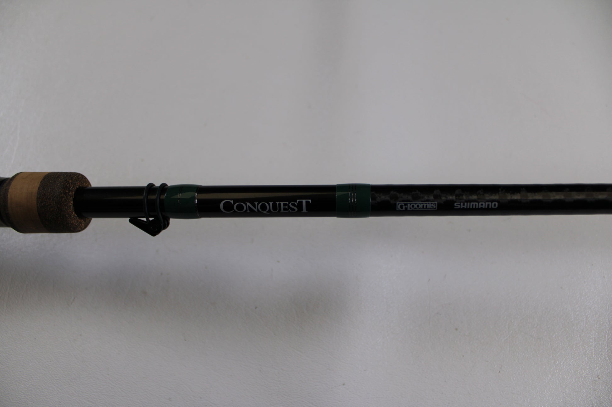 Close-up of the G. Loomis Conquest CNQ 905C MBR Used Casting Rod in very good condition, showing "CONQUEST" and "G.Loomis" logos on the black shaft with cork handle—ideal for our Rod and Reel Trade-In Program or for store credit.