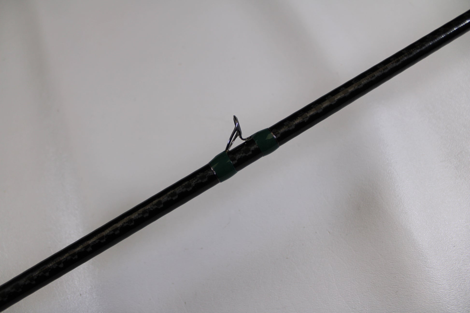A close-up of the G. Loomis Conquest CNQ 905C MBR Used Casting Rod in very good condition, featuring a black finish and green-threaded line guide—ideal for trading in through our Rod and Reel Trade-In Program.