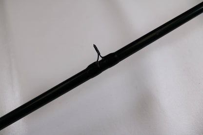 A close-up of the G. Loomis FGR863 7'2" Medium Heavy Used Casting Rod's dark green guide with metal loop, set against a white background—ideal for anyone exploring our rod and reel trade-in program.