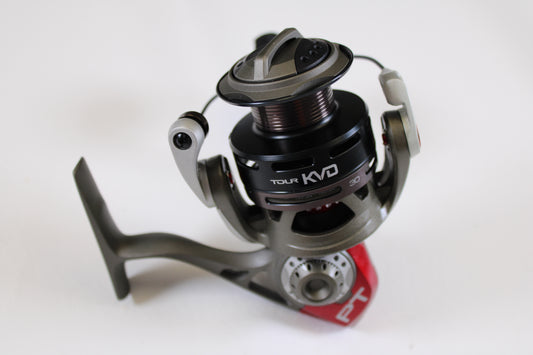 A close-up of the Quantum Tour KVD TKVD30 PTi 5.2:1 Used Spinning Reel in excellent condition, showing its black, silver, and red metallic finish on a white background—ideal for anglers upgrading via the Rod and Reel Trade-In Program.