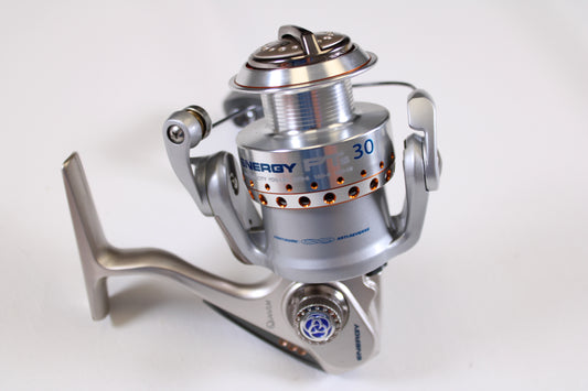 A close-up of the Quantum Energy Inshore PTs EI30PTSB 5.2:1 spinning reel in excellent used condition on a white background, featuring metallic silver and blue details—ideal for upgrades with our rod and reel trade-in program.