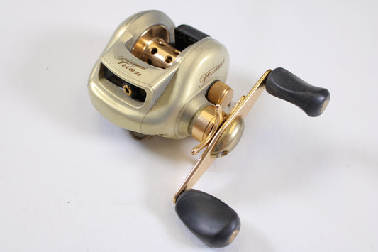 A Pflueger Trion PFLTRIONLPL 6.3:1 LH used casting reel in good condition, shown on a white surface—ideal for our rod and reel trade-in program or anyone seeking quality pre-owned gear.