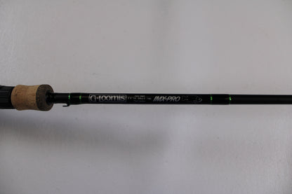 A close-up of the G. Loomis IMX-PRO 782c MBR 6'6" Medium Used Casting Rod in excellent condition shows the brand and model on its black rod with green accents and a cork handle—ideal for Rod and Reel Trade-In or checking used gear.