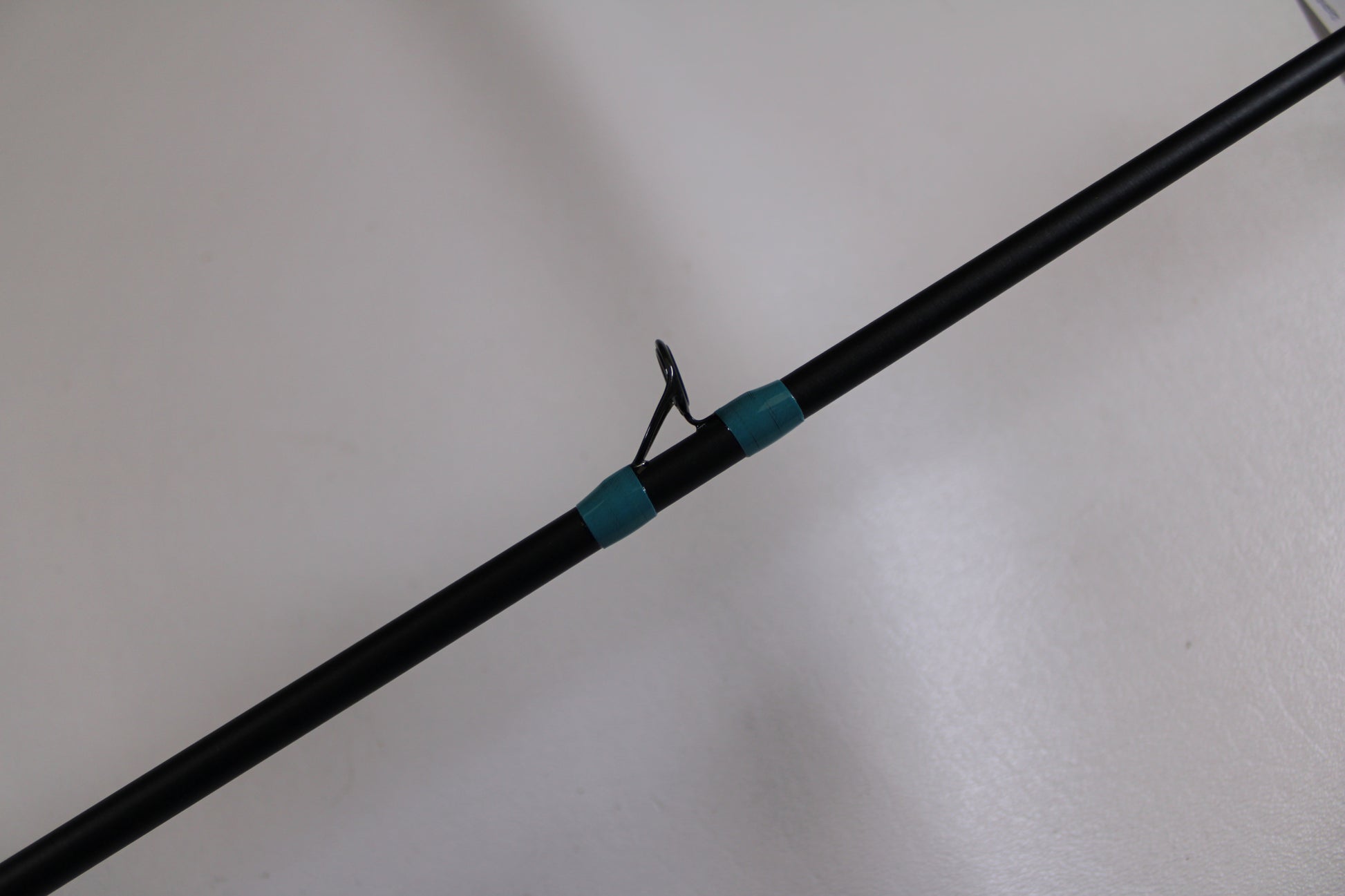 A close-up of the G. Loomis NRX+ 781c Inshore 6'6" Med-Lite Used Casting Rod in excellent condition, featuring a metal guide ring and teal thread wraps—ideal for our Rod and Reel Trade-In Program or upgrading your gear.